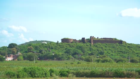 an ancient fort or castle abandoned and covered with thick green forest on a hill top in madhya pradesh india