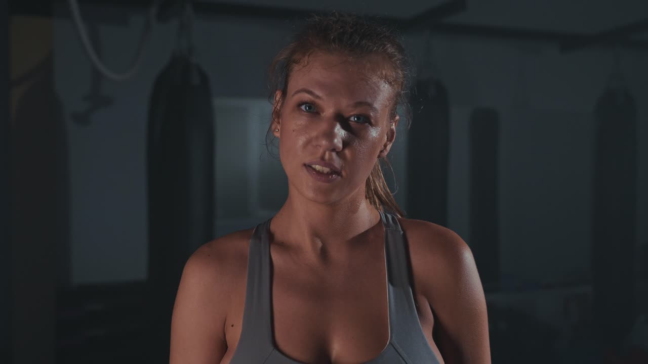 Tired Female Boxer Wiping Sweat After Intense Workout in Gym