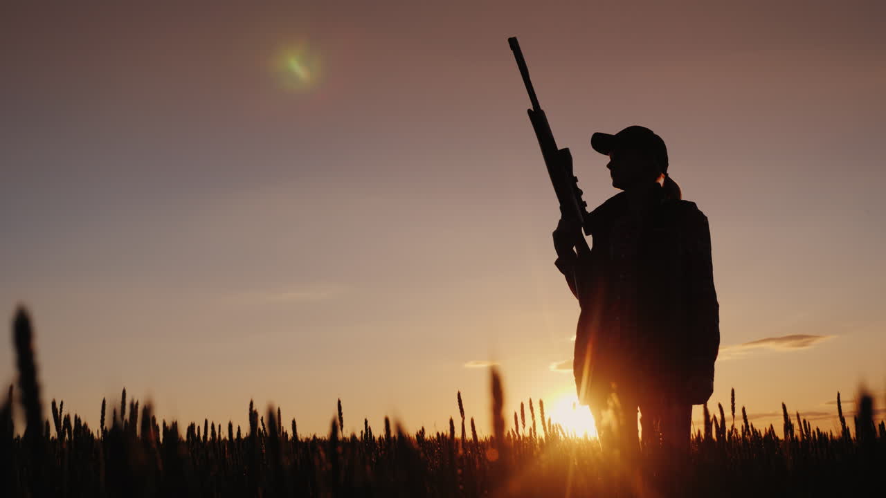 4k 비디오 촬영 일몰 스포츠의 광선에 라이플을 가진 여자의 실루엣