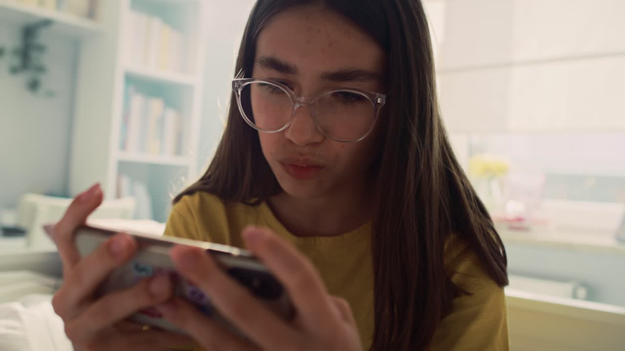 adolescente caucásica jugando un juego en el teléfono y siendo muy concentrado