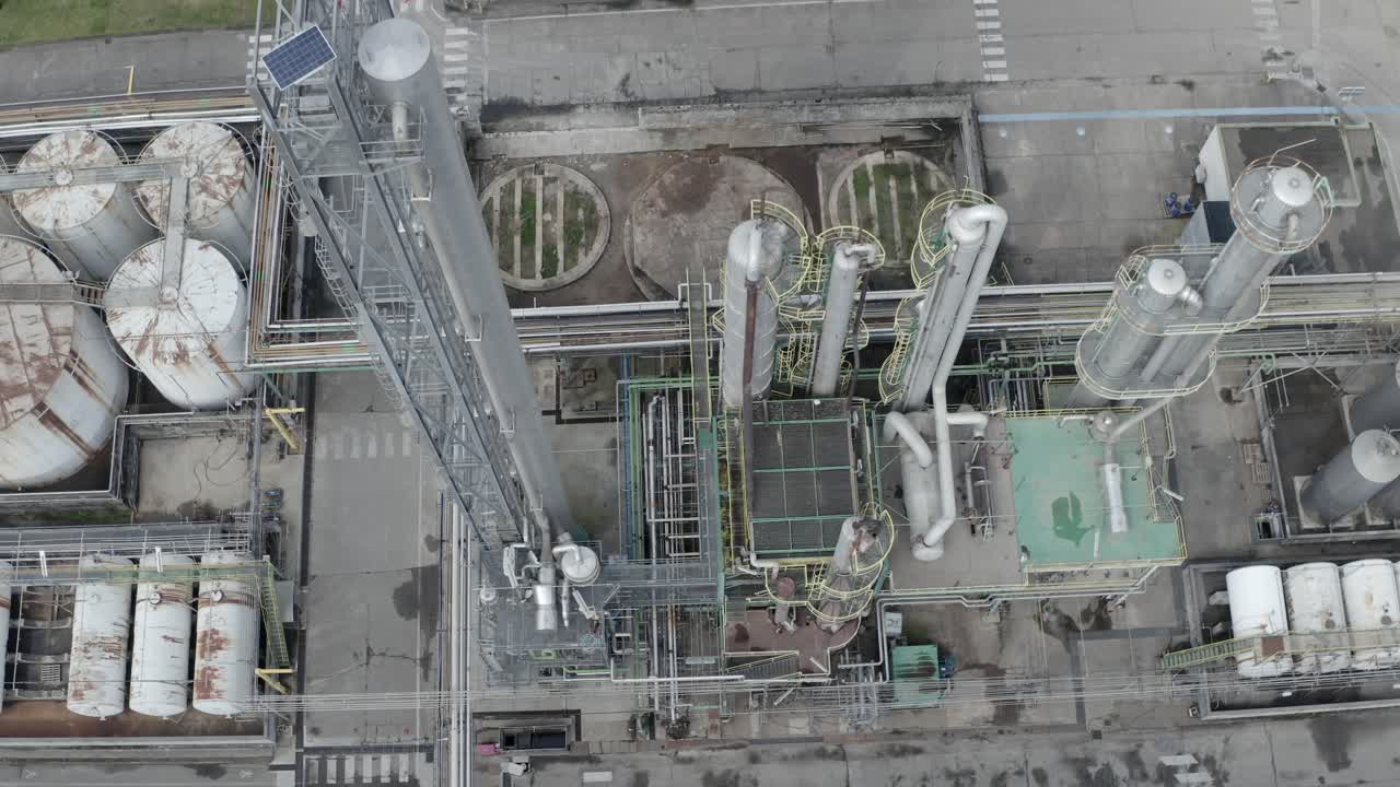 Aerial top-down circling descending view of industrial processing unit with pipes, tanks, and cooling tower elements, Veille-Saint-Girons, France