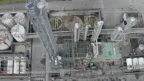 aerial top-down circling descending view of industrial processing unit with pipes, tanks, and cooling tower elements, veille-saint-girons, france
