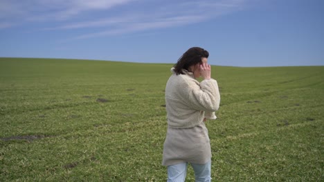 a young beautiful brunette girl walks through a green meadow.