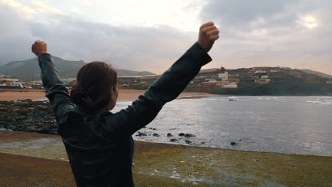 shot-of-a-woman-who-raises-her-arms-in-victory-on-the-beach-of-Boca-Barranco-in-the-city-of-Galdar,-on-the-island-of-Gran-Canaria