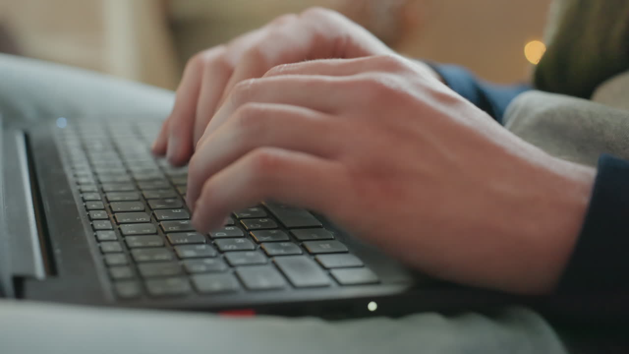 Digitazione con dita concentrate. Scrittura fluida in un ambiente accogliente. Lavoro creativo svolto durante le confortevoli ore serali. Freelance che compone diligentemente un articolo su un divano illuminato da luce soffusa.