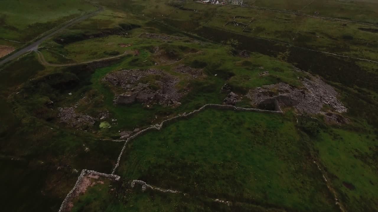 Green landscape at dusk in a cloudy day. A stone farm surrounded by huge fields close to the cliffs of Moher in Ireland. Aerial shot at the end of the day.