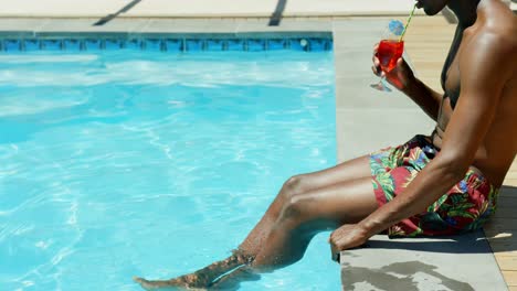 Low-section-of-black-man-drinking-cocktail-drink-near-swimming-pool-4k