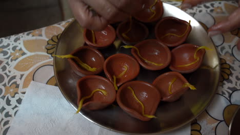 top view of a plate full of clay pots being prepared by an indian woman wearing gold bangles during the hindu festival of diwali