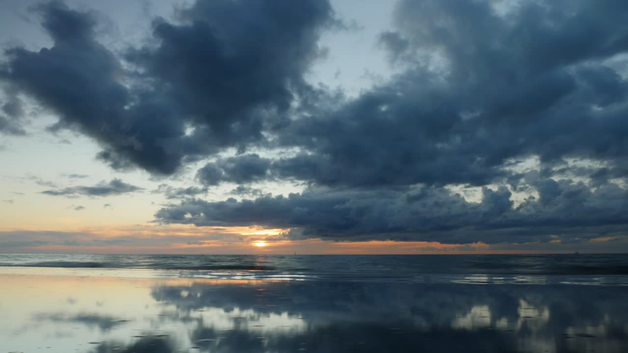 lapso de tiempo de una hermosa puesta de sol nublada y su reflejo en un charco de agua en una playa báltica en letonia