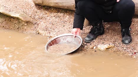 person panning for gold in muddy water