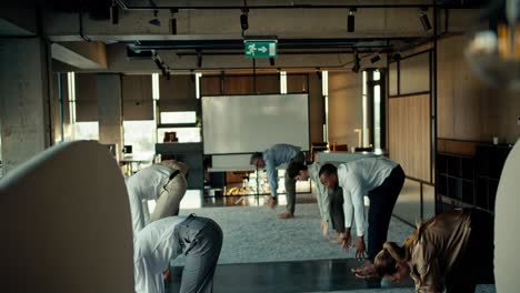 Overview-of-a-group-of-business-people-in-business-attire-doing-yoga-during-a-break-at-work-in-the-office.-Taking-care-of