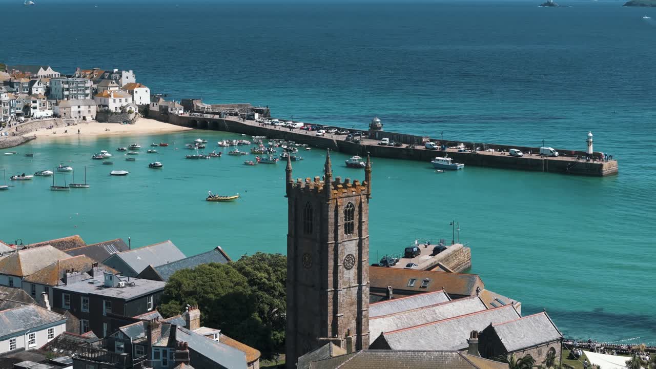 Aerial approach circling right around St Ives church with vibrant bay in background