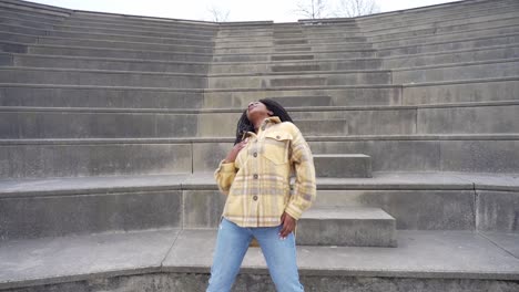 smiling black woman dancing on steps in park