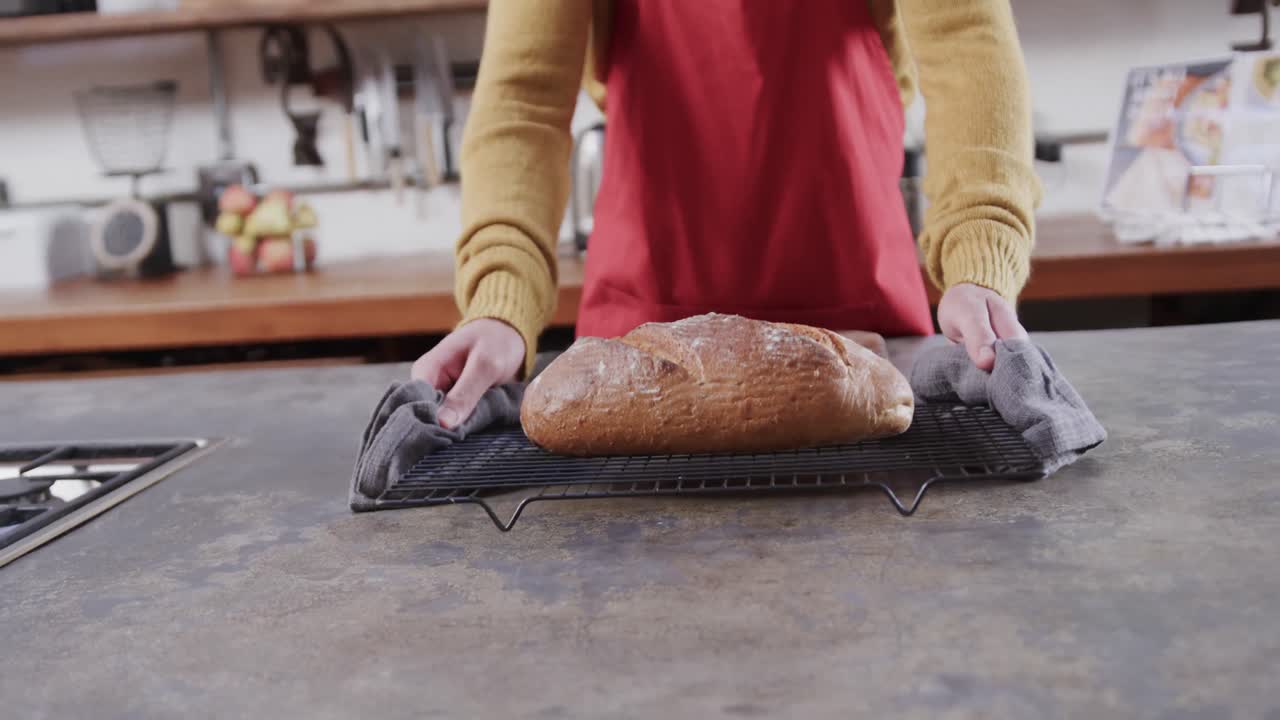 Midsection of caucasian man putting bread on worktop in kitchen, slow motion