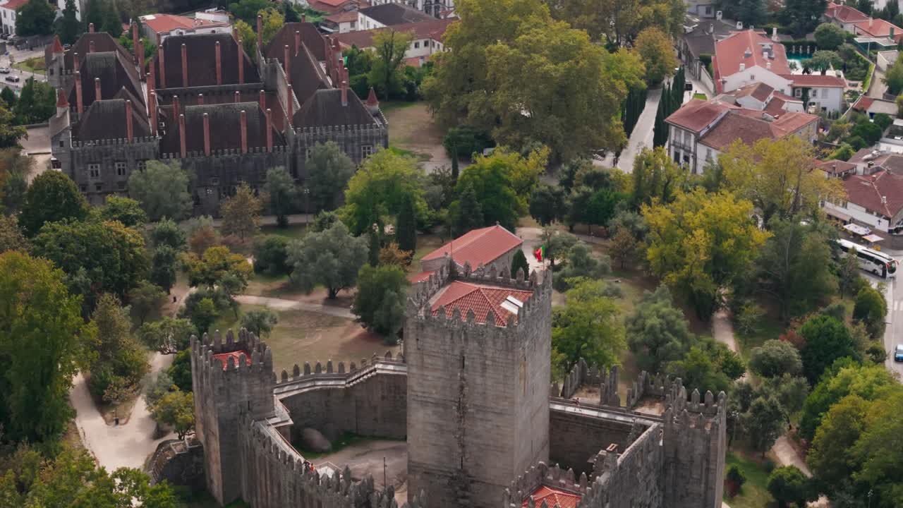 Luftfoto af Guimarães-slottet, der rejser sig over grønne haver og gamle by gader