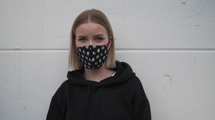Portrait of young woman with protective face mask looking at camera slow motion