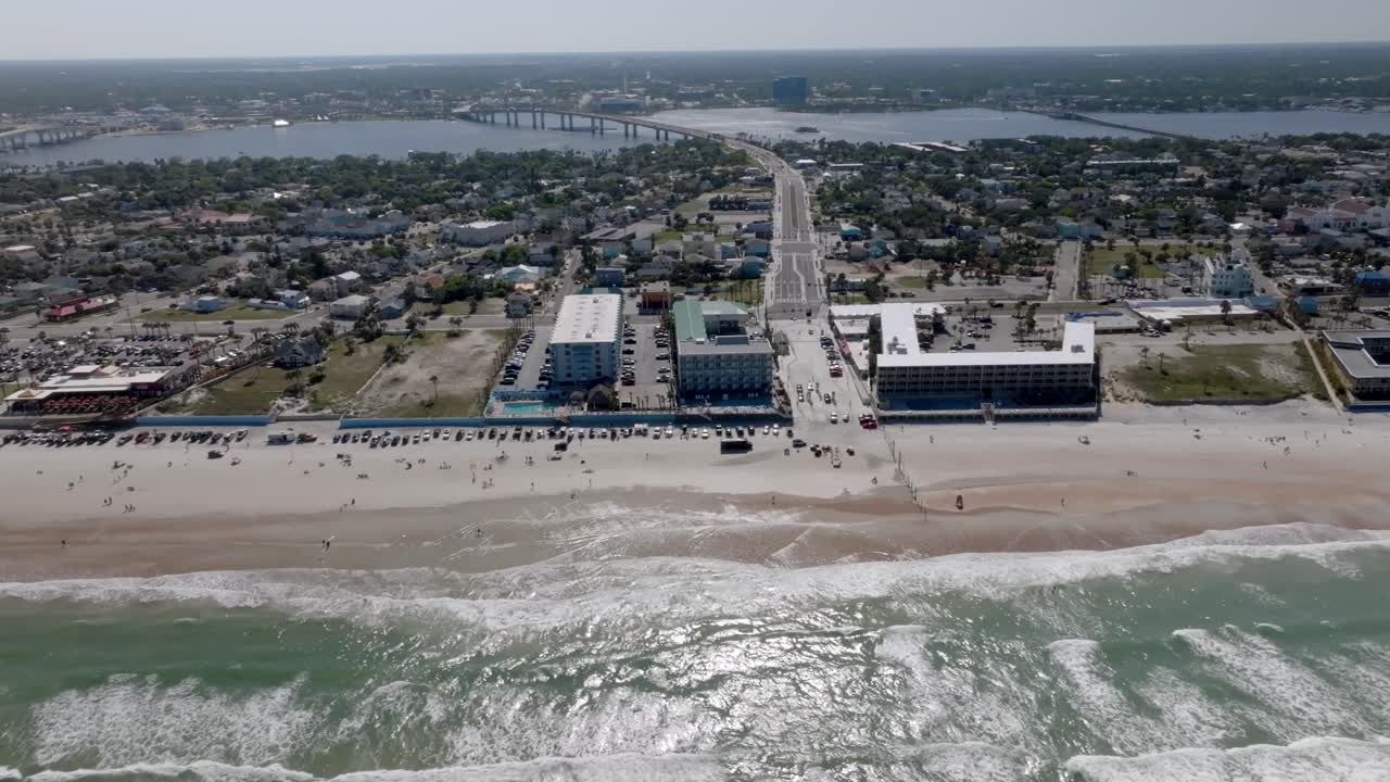Daytona Beach, Florida with vehicles and people on the beach with drone video moving right to left.