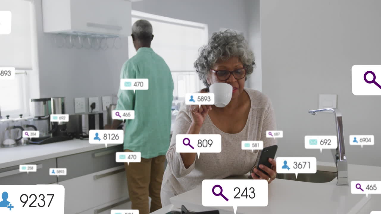 Using smartphone in kitchen, elderly woman interacting with animation notifications