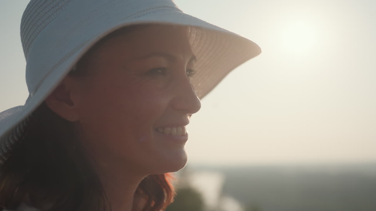 close up of young woman holding bouquet of wildflowers with warm sunlight streaming through leaves and petals, creating golden glow as she gently lifts flowers near face