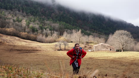 young trekker adventurers hiking on a mountain trail in remote area leaving behind old stone house cottage for farming