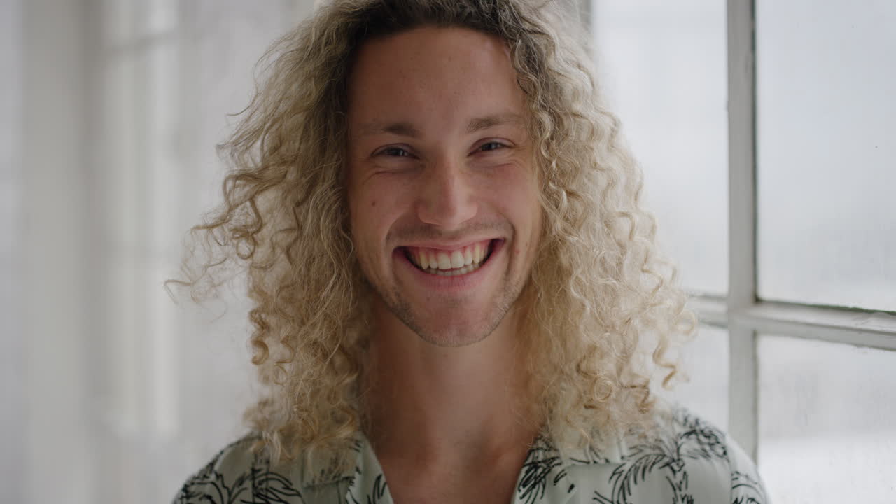 retrato de un joven hombre rubio sonriendo con confianza mirando a la cámara disfrutando del estilo de vida estudiantil independiente en un nuevo apartamento
