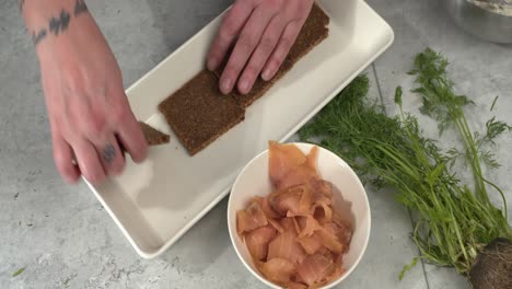 rye bread slices laid onto kitchen platter near smoked salmon and dill