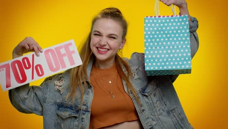 cheerful teen girl showing shopping bags and up to 70 percent off inscriptions banner, black friday