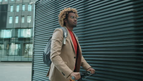 young african american man going to work on e-scooter