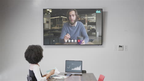 mujer de negocios afroamericana en videollamada con un colega caucásico en la pantalla