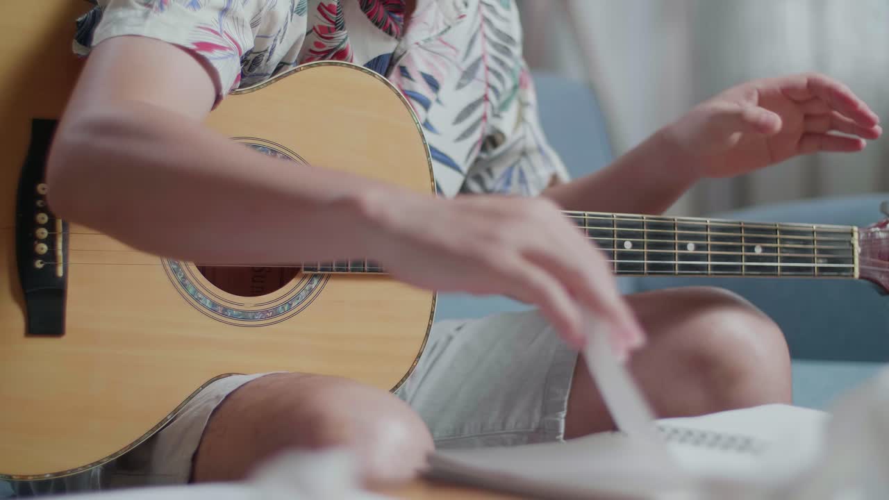 아시안 남자 작곡가가 기타를 은 종이를 던지고 집에서 음악을 작곡하는 동안 두통을 고 있습니다.