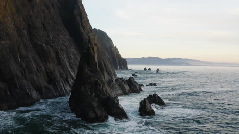 Drone-flight-over-small,-sharp-rock-ridge-in-Pacific-Ocean-along-Oregon-Coast