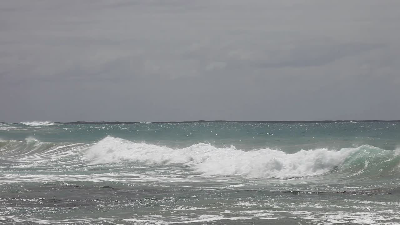 위의 흐린 하늘 아래에서 밀려오는 먼 파도