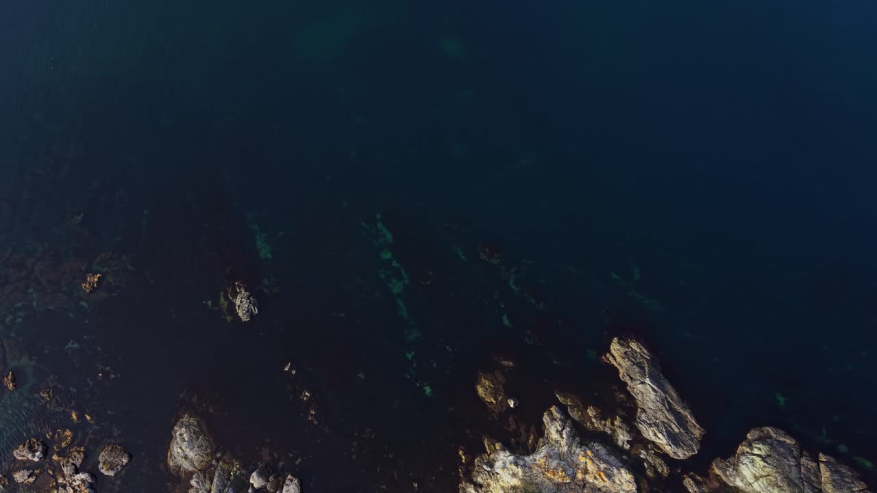 View of rocky coast with clear blue waters in aerial perspective