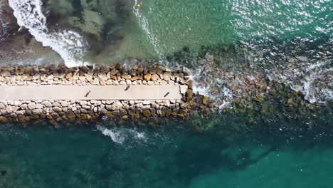 old ruined pier on pebbly beach with transparent water