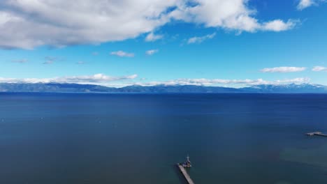Drone-shot-overlooking-a-dock-on-the-shores-of-Lake-Tahoe-with-blue-water