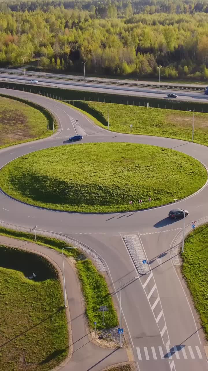 Vertical descend roundabout of residential neighborhood with open green spaces as cars enter and exit