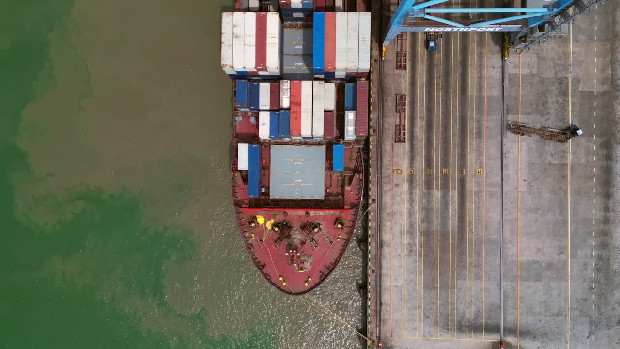 gantry cranes moving containers from a docked cargo ship, illustrating global shipping and supply chain logistics. Unique aerial view drone camera pointing down