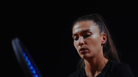 mujer concentrándose en la raqueta de tenis por la noche