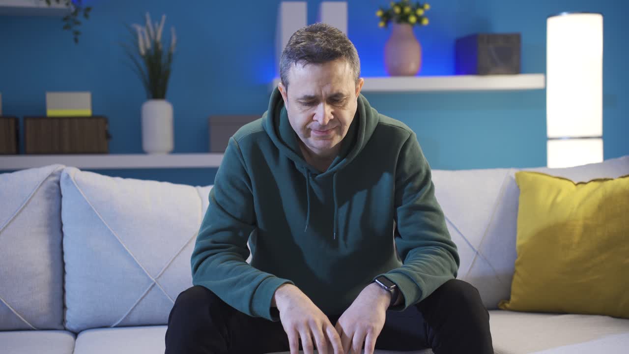 un hombre maduro de mediana edad deprimido sentado en el sofá, un hombre frustrado que se siente solo por dentro.