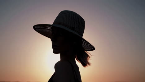 elegant woman in hat silhouette at sunset
