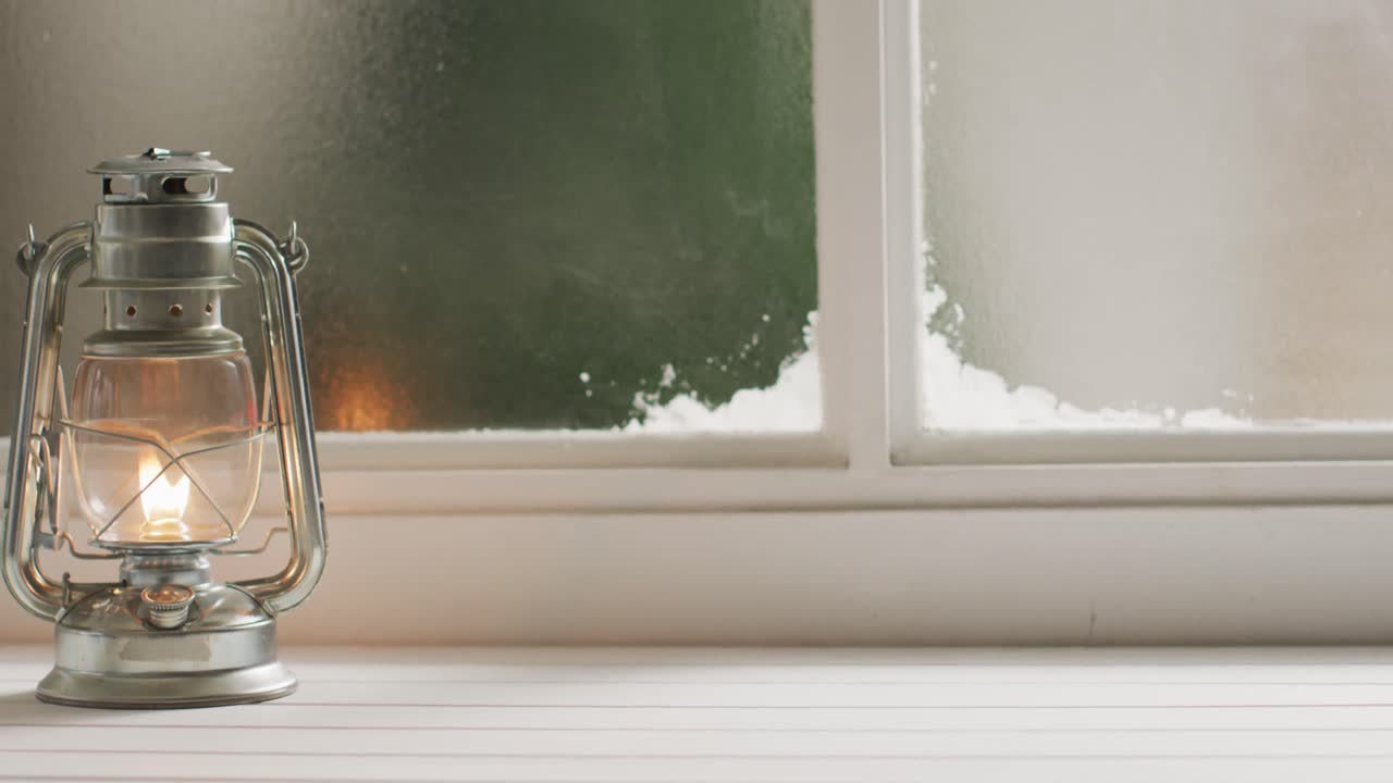 얼어붙고 눈  ⁇ 인 창문 위에서 반 ⁇ 이는 빈티지 오일 램프의 비디오