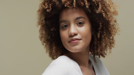 Happy-biracial-woman-with-dark-hair-on-beige-background,-slow-motion