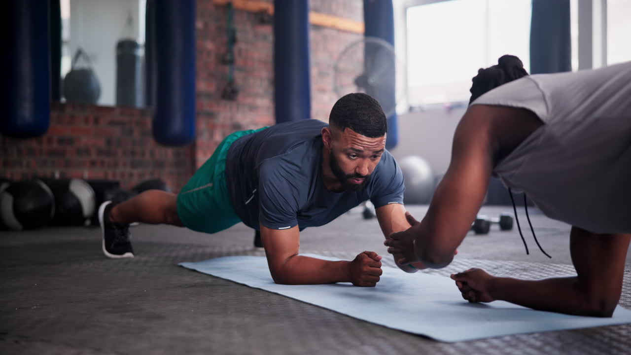 hombre haciendo ejercicio de tabla con entrenador personal en el gimnasio