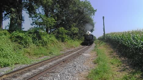 tren de vapor resoplando a lo largo de las tierras de cultivo amish visto por un dron