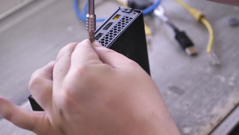 Support-technician-fixing-computer-screwing-back-cover-in-his-office,-close-up