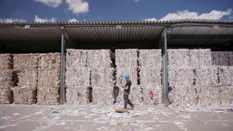 worker counting pressed bound paper bales at recycling facility