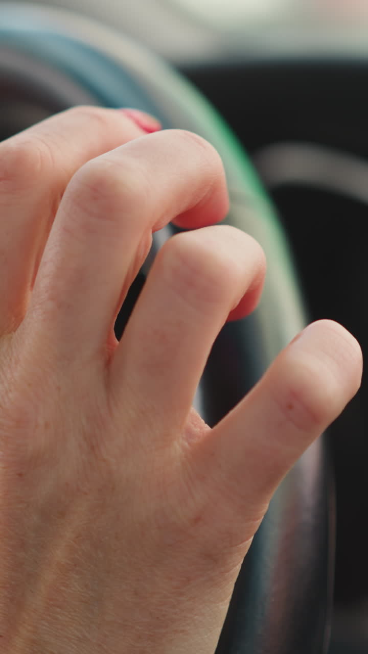 여성 운전자는 스티어링 을 들고 기대하며 손가락을 니다. 서두르는 사람은 흐릿한 배경 클로즈업에서 교통체증에 서서 움직일 기회를 기다립니다.