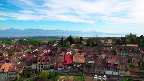 Aubonne,-Switzerland,-Aerial-of-town-buildings-with-French-alps-and-Lake-Geneva-on-the-background