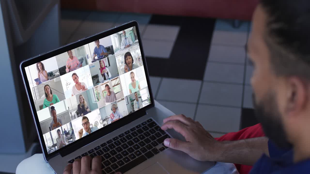 African american man having a video conference with office colleagues on laptop at home