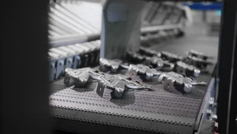 close up of an automated robotic arm taking a raw metal car part from a conveyor belt and transferring it to the next stage in the production factory